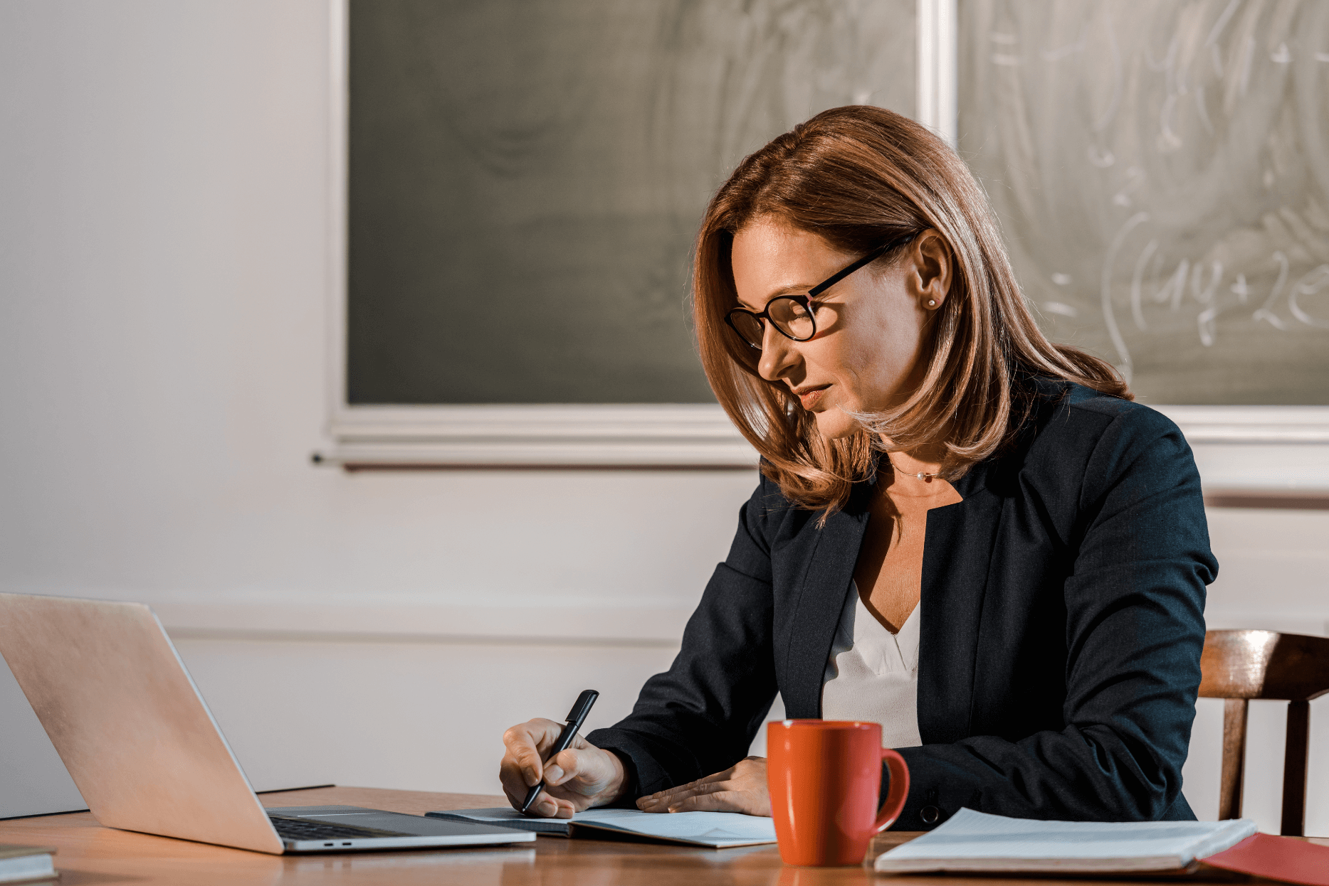 Teacher sitting alone at desk writing notes